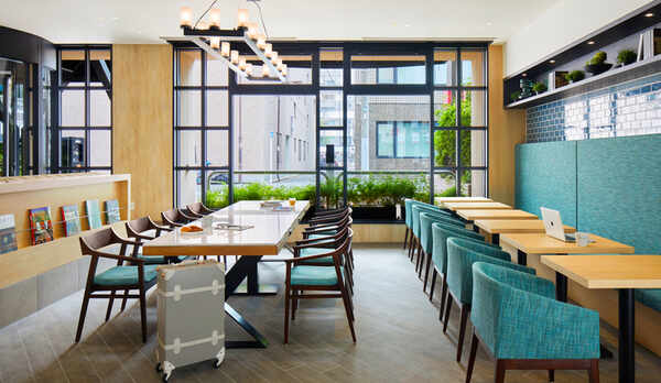 朝食時間以外は&rdquo;コワーキングスペース&rdquo;として開放。長机には電源を備えPC作業に便利