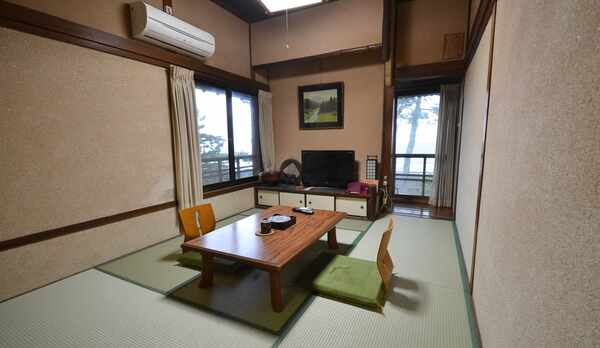 【本館：2階海側和室（一例）】海沿いの窓からは高々と立つ松の木と、伊勢湾が一望できます。