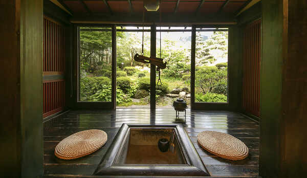 豊かな緑を眺める囲炉裏付の広縁。柔らかな熱とともにおくつろぎください。